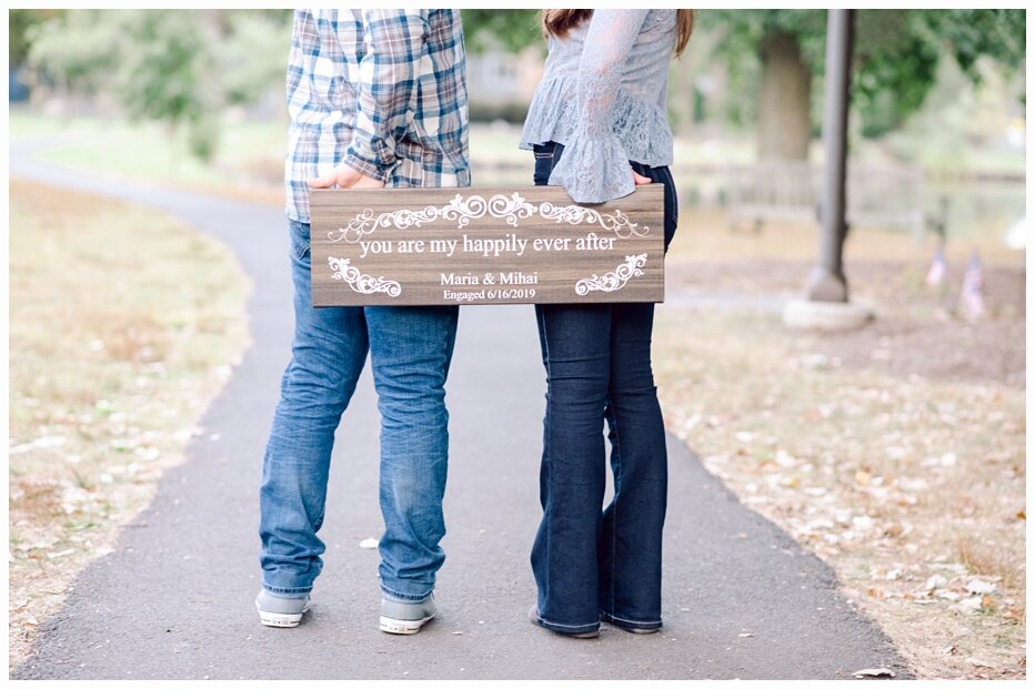 engaged couple holding a pretty wooden sign with their wedding date on it