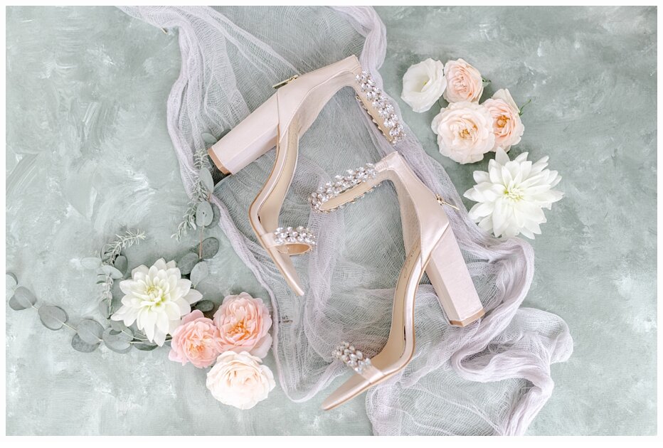 wedding shoes on a veil surrounded by flowers