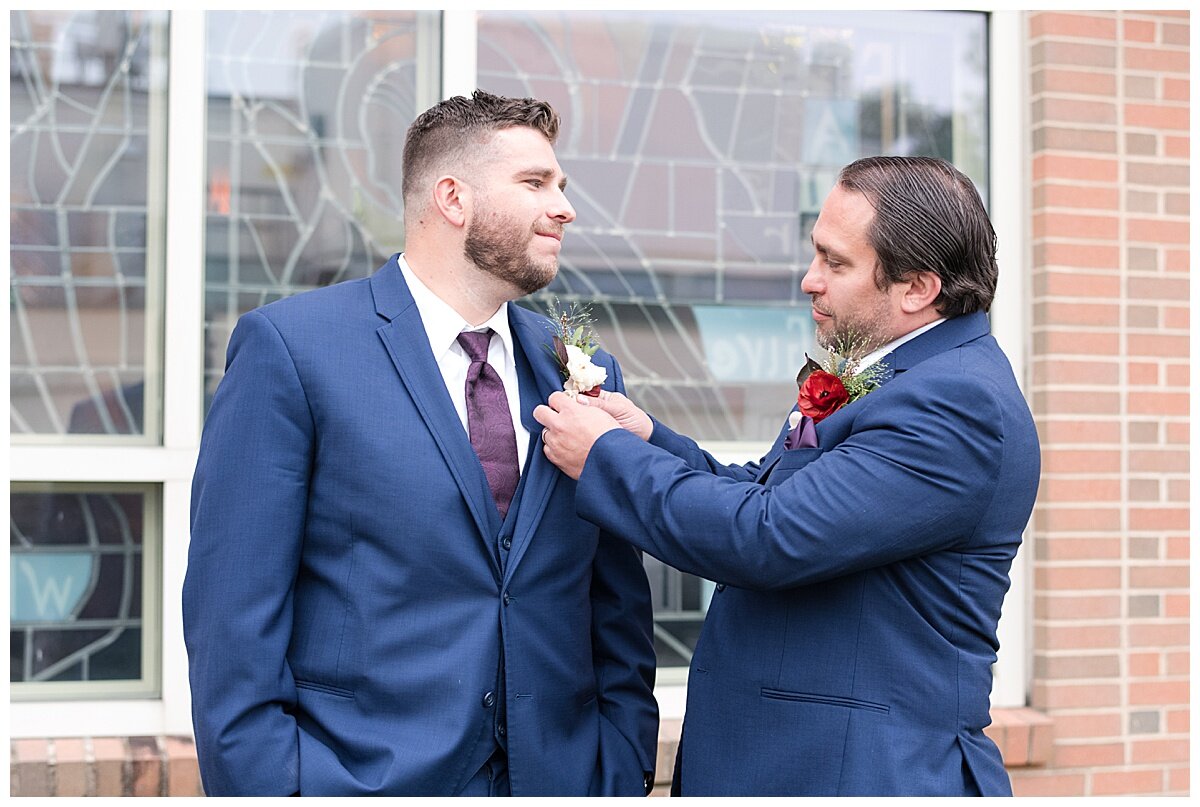 groom and his brother putting on his boutainnaire