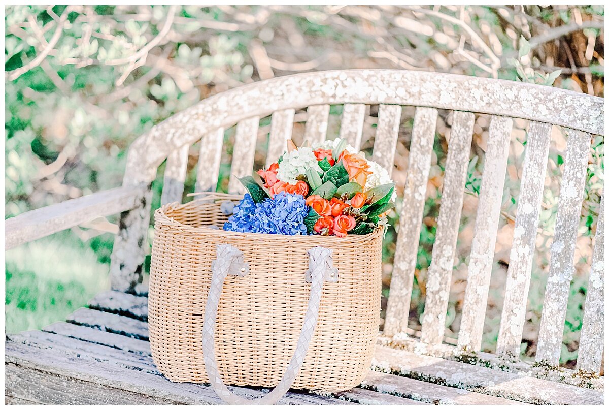 a bench with a straw basket with flowers in it