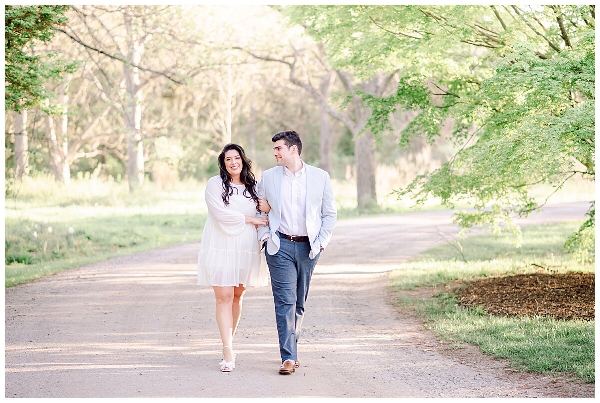 engaged couple walking on a path in a park