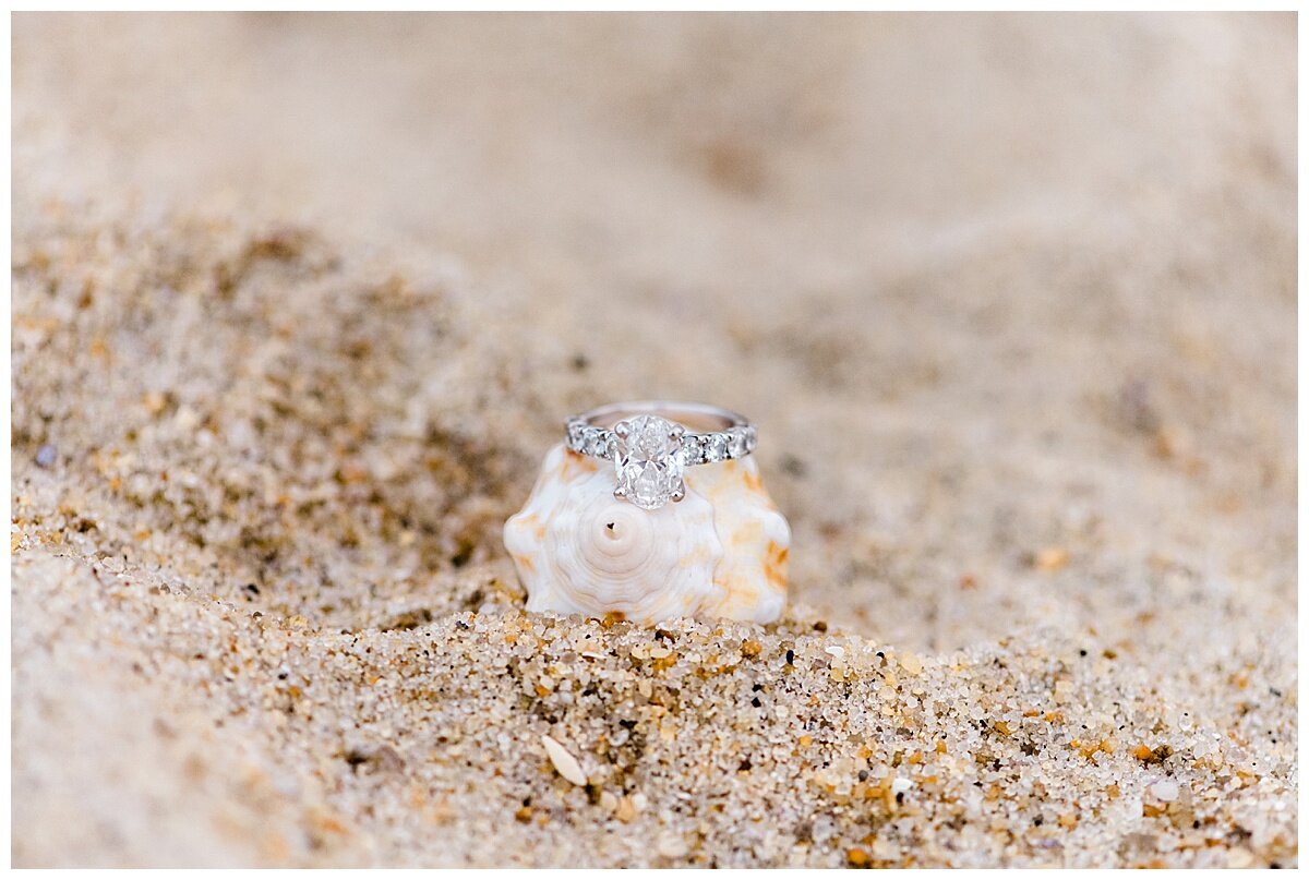 pretty engagement ring on a shell in the sand