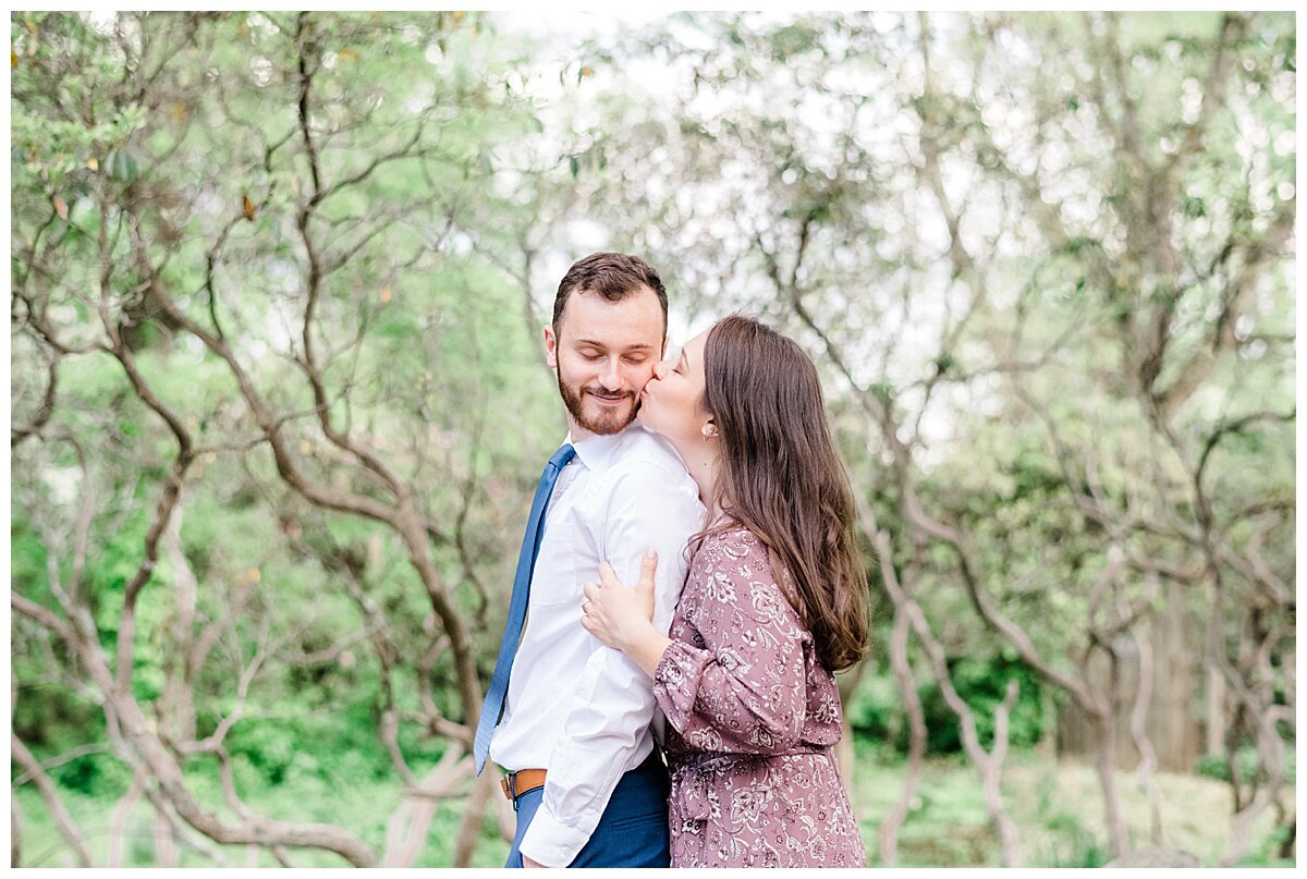 engaged couple kissing in a garden