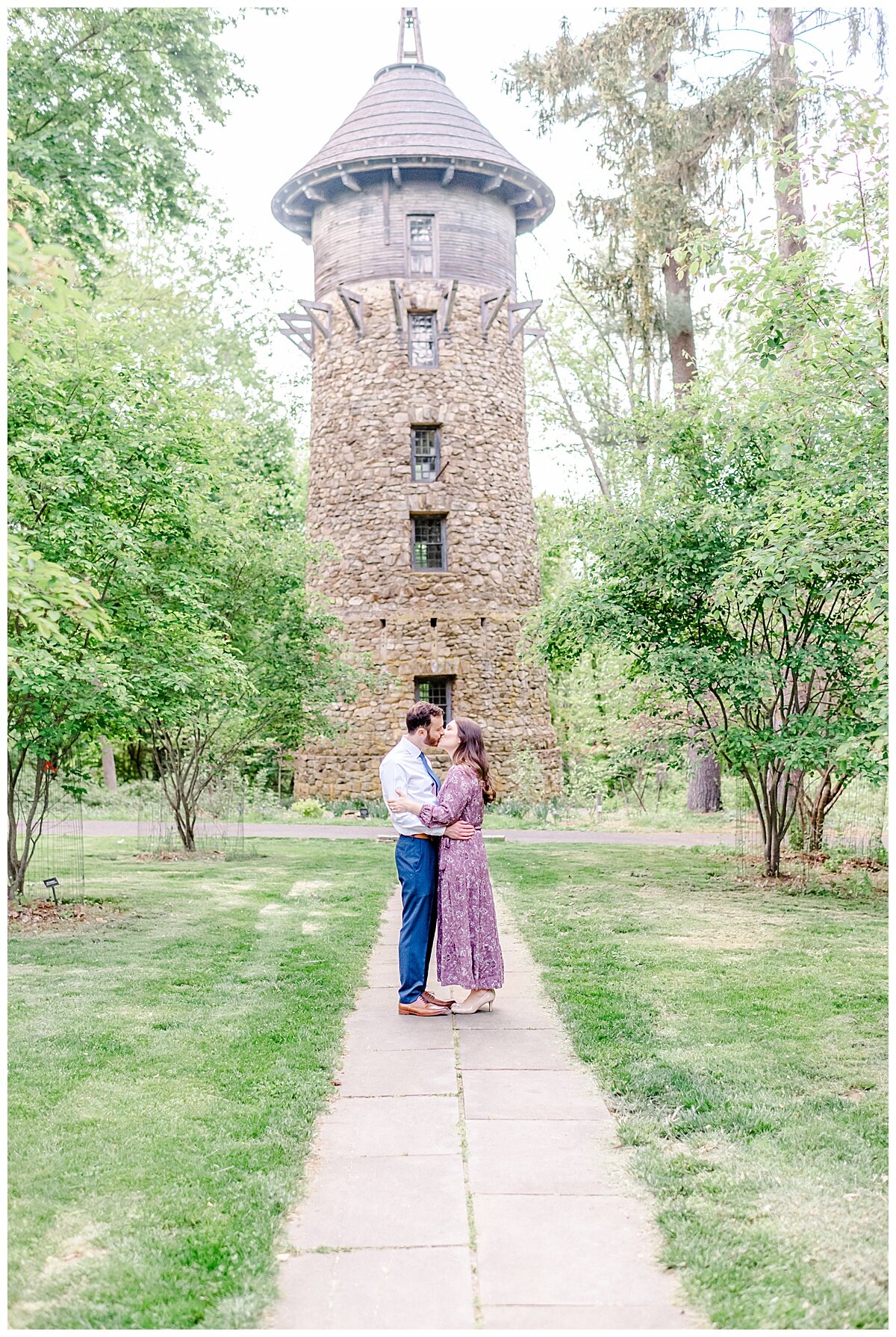 engaged couple in front of a brick water tower hugging