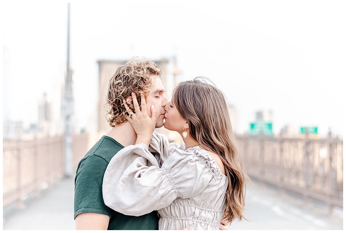 engaged couple kissing on the brooklyn bridge