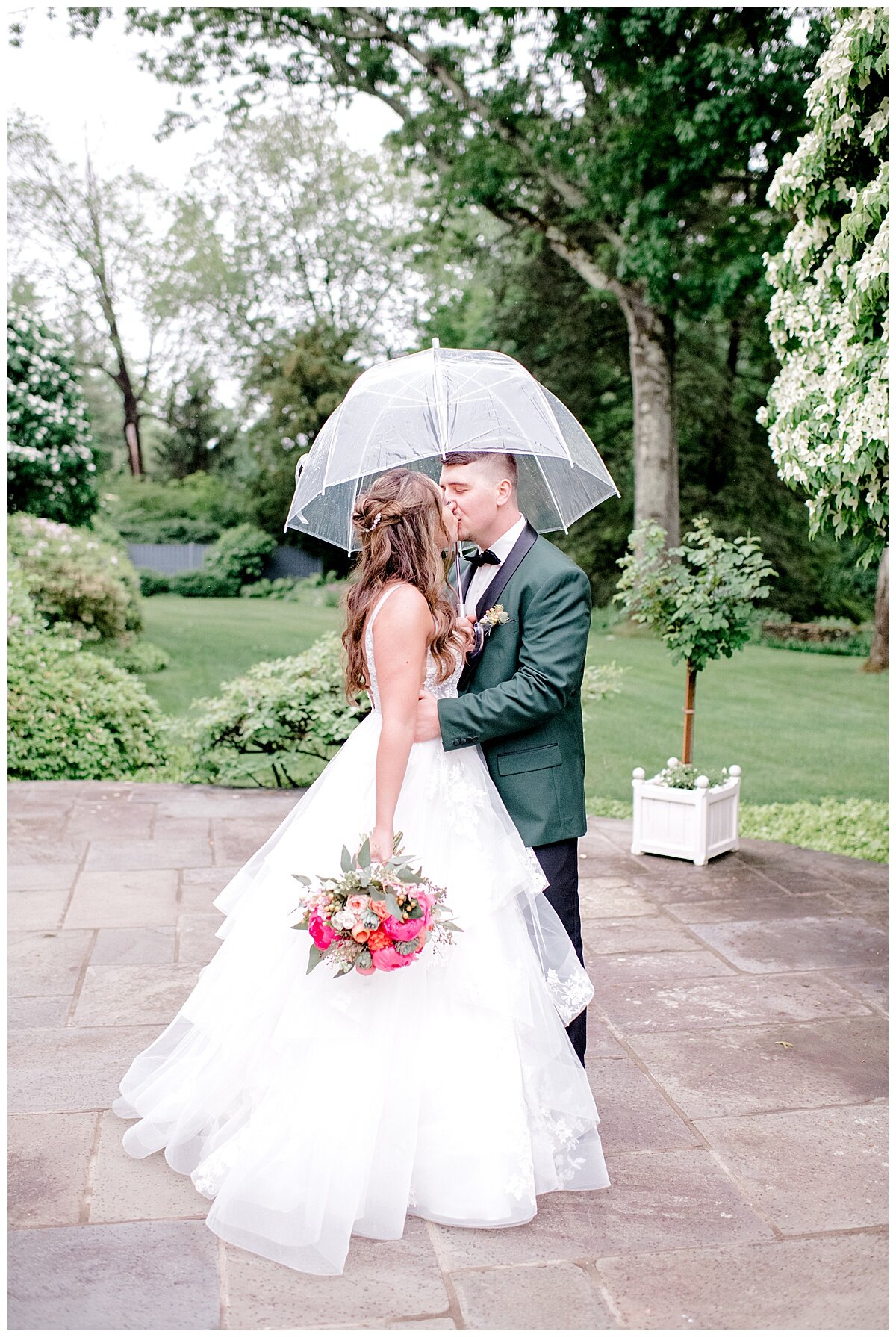 bride and groom kissing under an umbrella in the rain