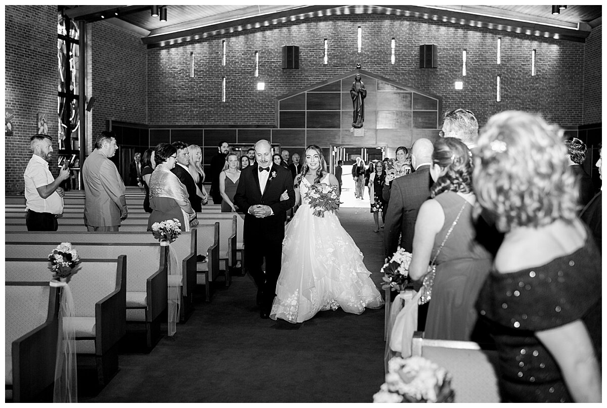 dad escorting his daughter down the aisle in church on her wedding day