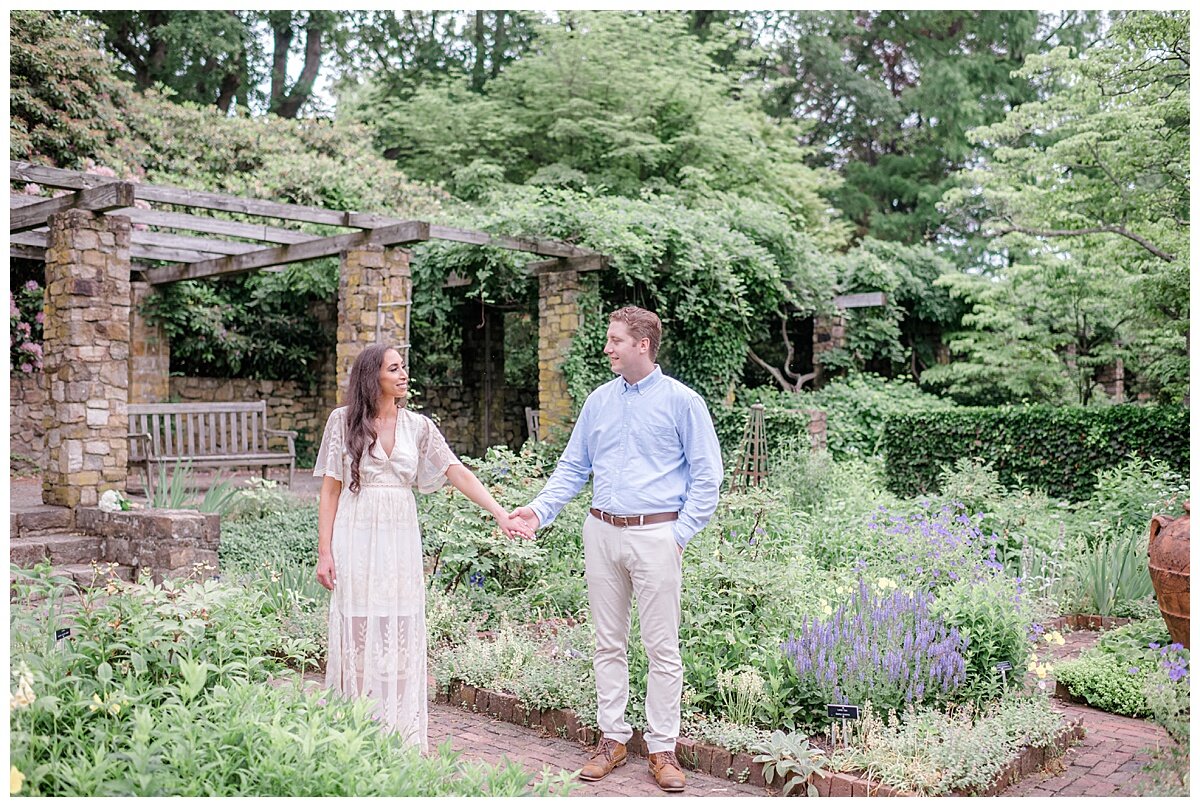engaged couple in a pretty garden holding hands