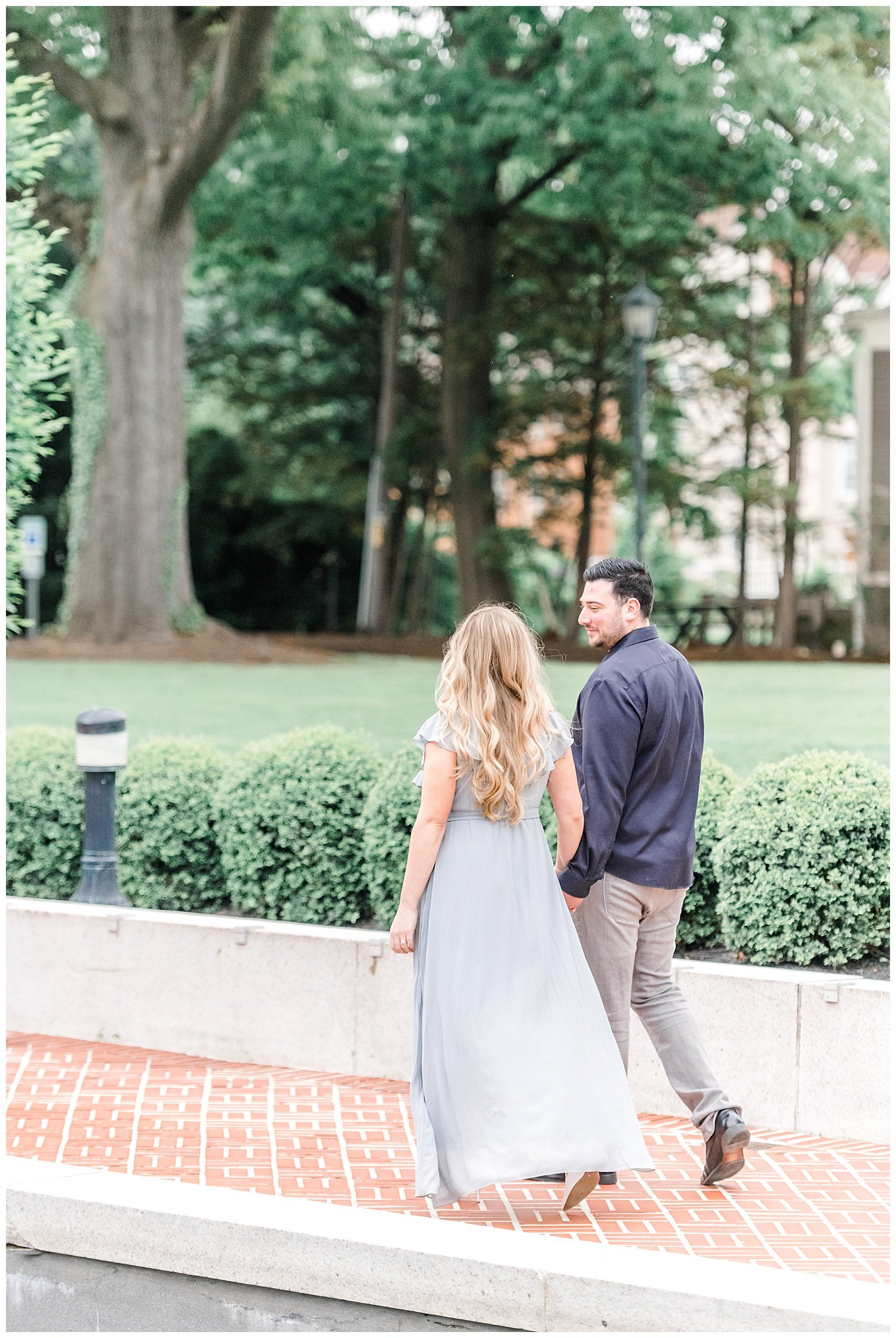 engaged couple walking by a pond