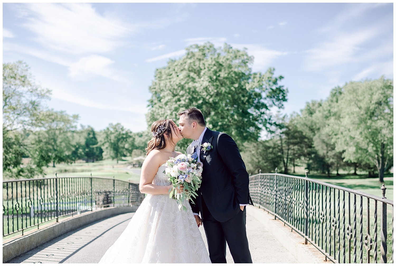 bride and groom kissing on a bridge