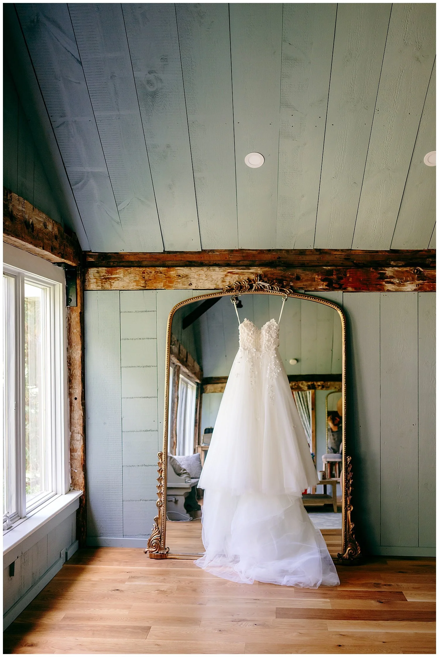 wedding gown hanging on pretty floor length mirror in bridal suite