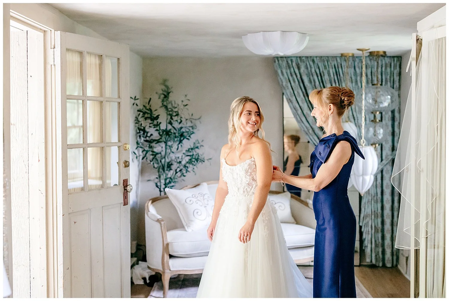 mother of the bride helping her daughter into her wedding gown