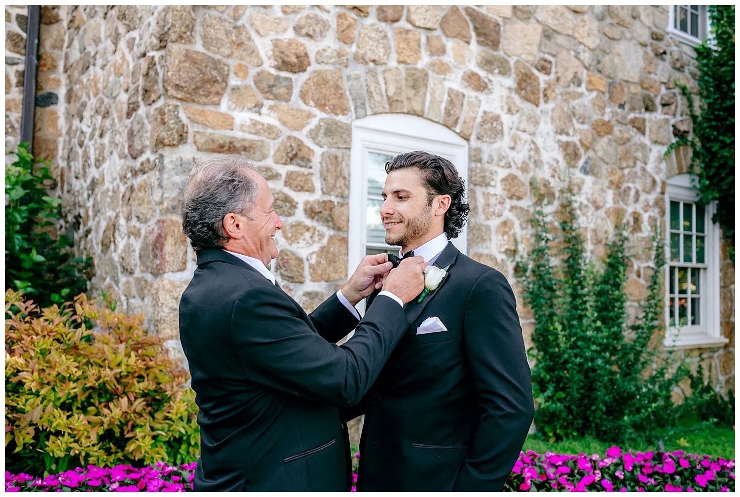 father fixing son's bow tie on wedding day