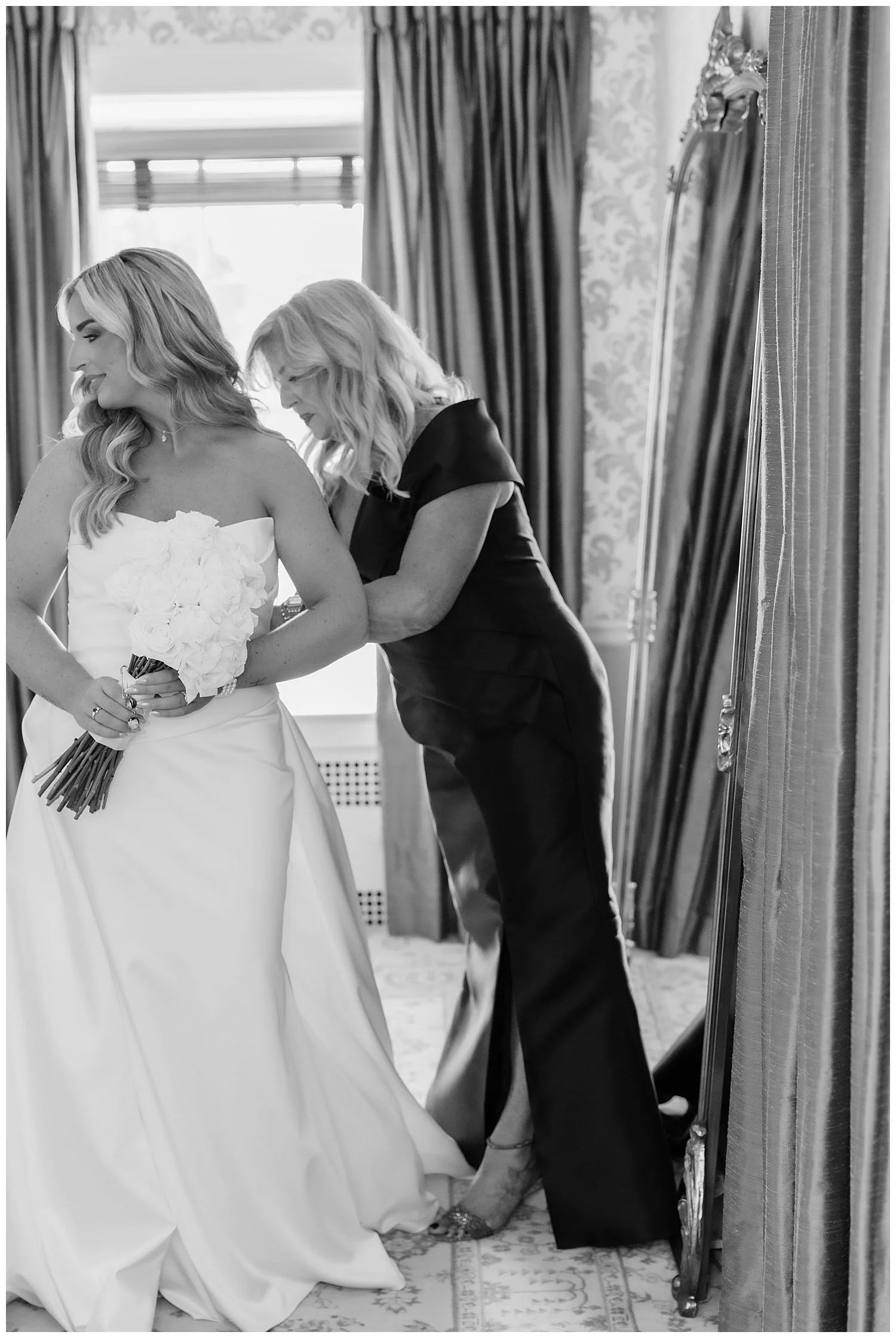 mom helping daughter into bridal gown