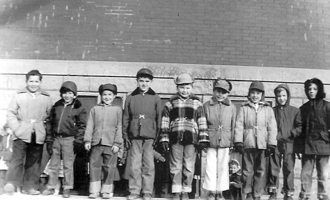 Second Grade boys, winter 1954-1955, standing on sidewall of cement sandbox. L-R: Bill Muck, Gary Beals, Doug Thomas, Vernon Seieroe, Don Evans, Robert Van Elsen, Dennis Conn, Dick Ward, Craig Garrett. I was wearing a bright red parka.