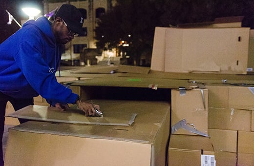 Wilson Meeks, 5th-year architecture student, puts the finishing touches on Phi Beta Sigma's massive cardboard box structure erected in Bosco Plaza during Sleep Out for the Homeless Thursday night. The members of the fraternity spent the night in the structure to raise awareness for the homeless and those below the poverty line in Manhattan and Riley County.