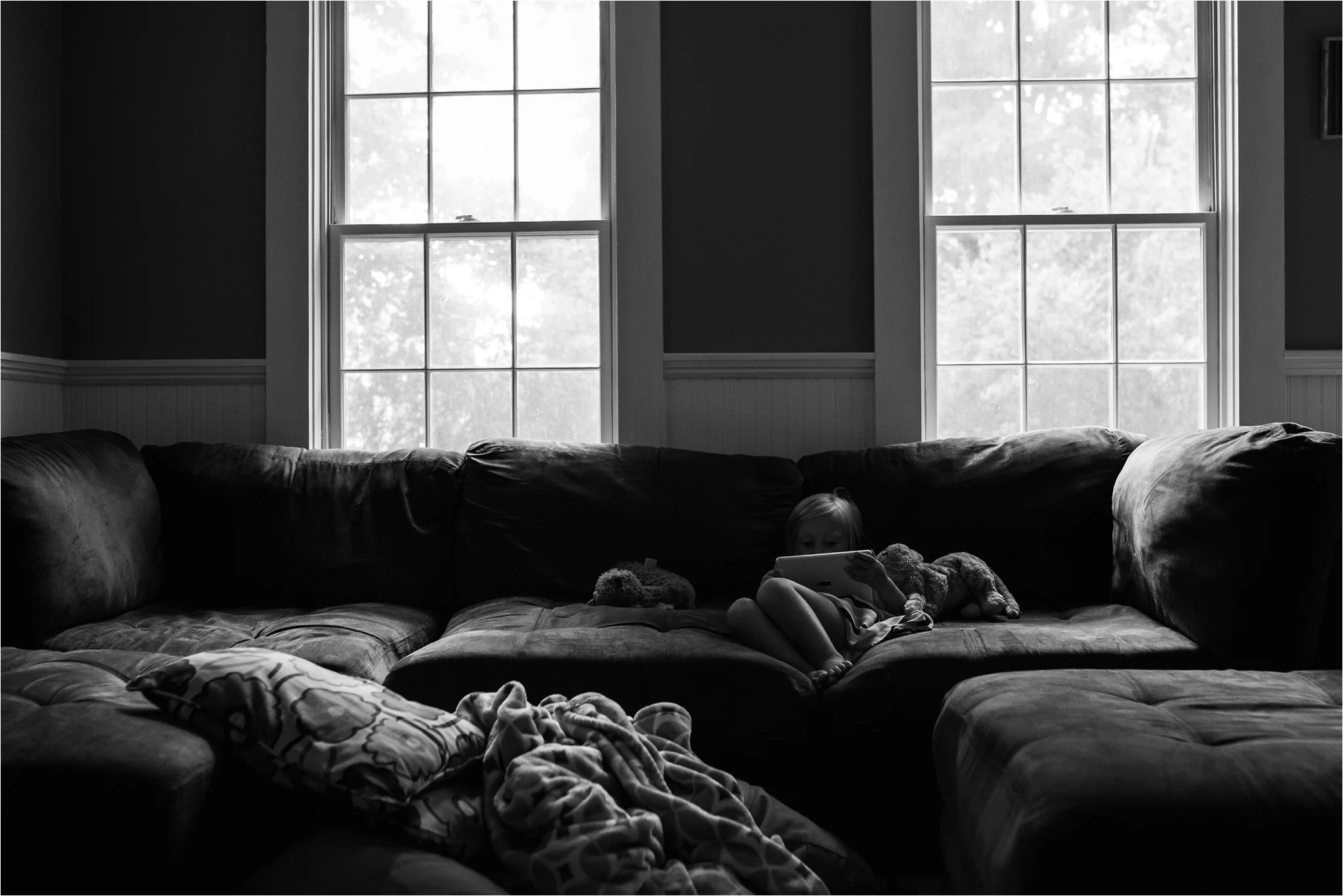 little girl sitting on the couch playing on the ipad