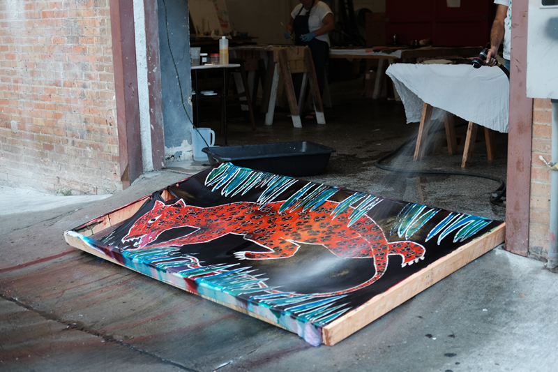 Manik rinses off a finished piece in the alley. 