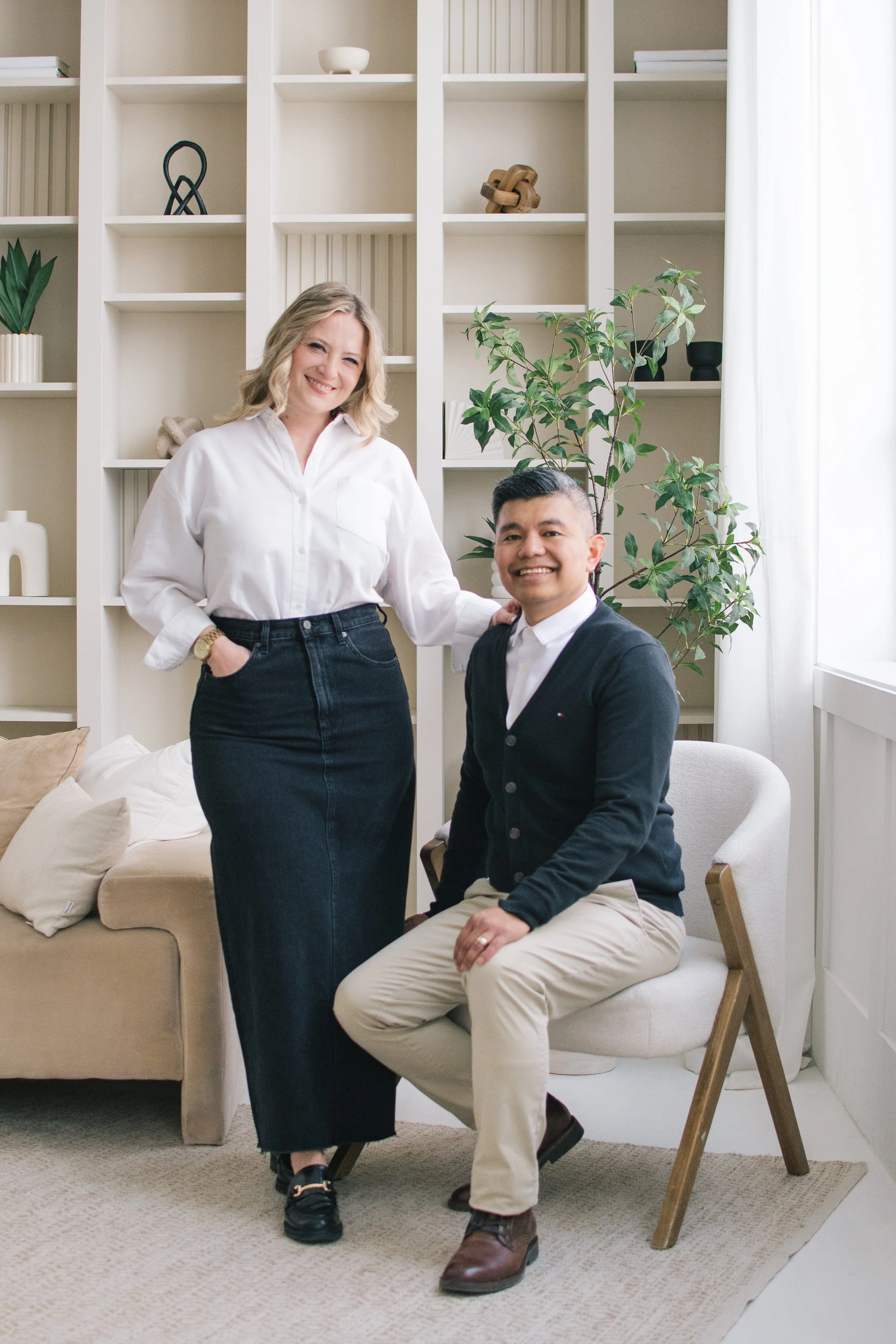 Husband and wife wedding photographers posing together for their brand portrait in a bright studio space