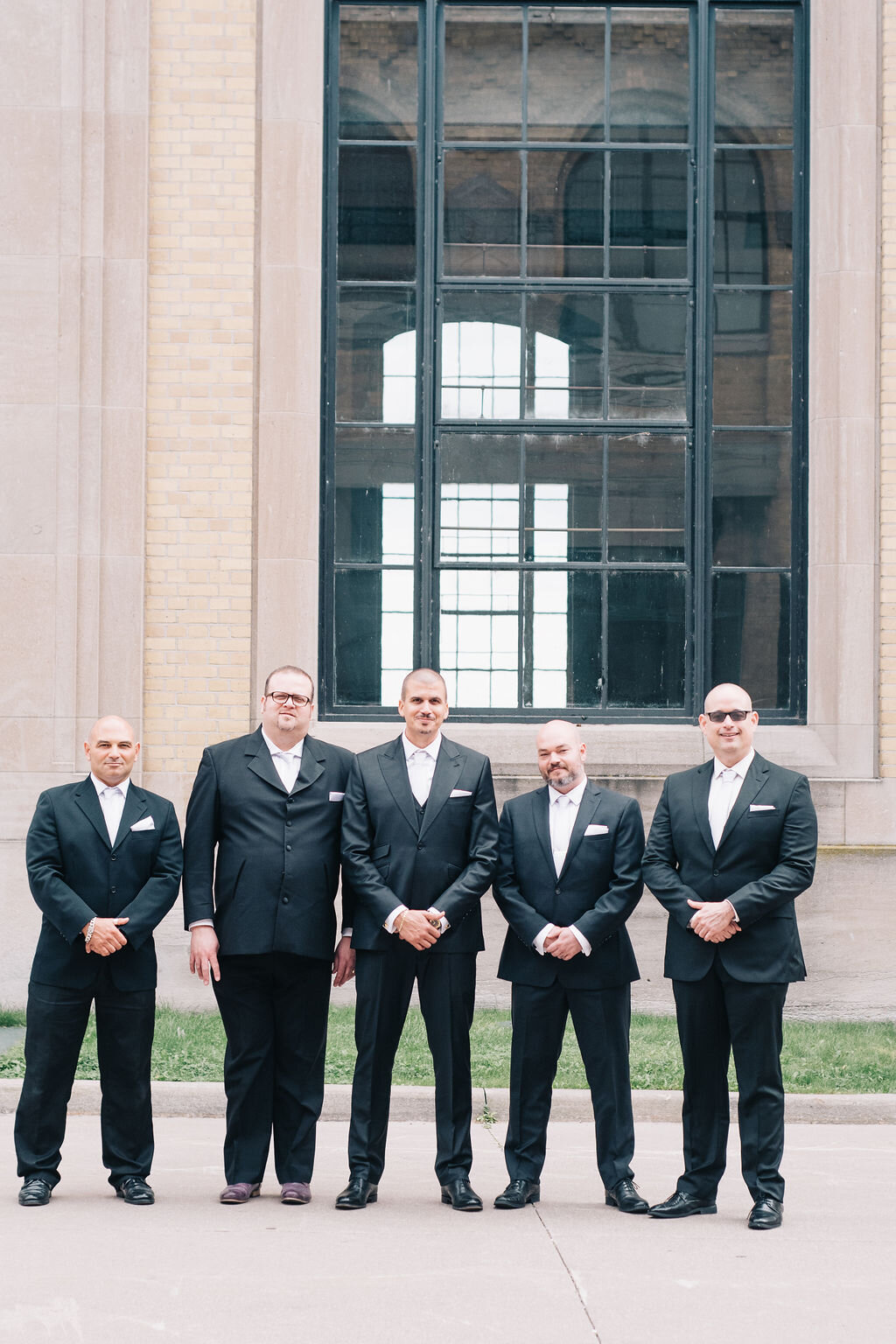 Toronto groom and his groomsmen at the Toronto bride and groom and their wedding party walk past the impressive buildings at the R.C. Harris Water Treatment Plant on groom's wedding day