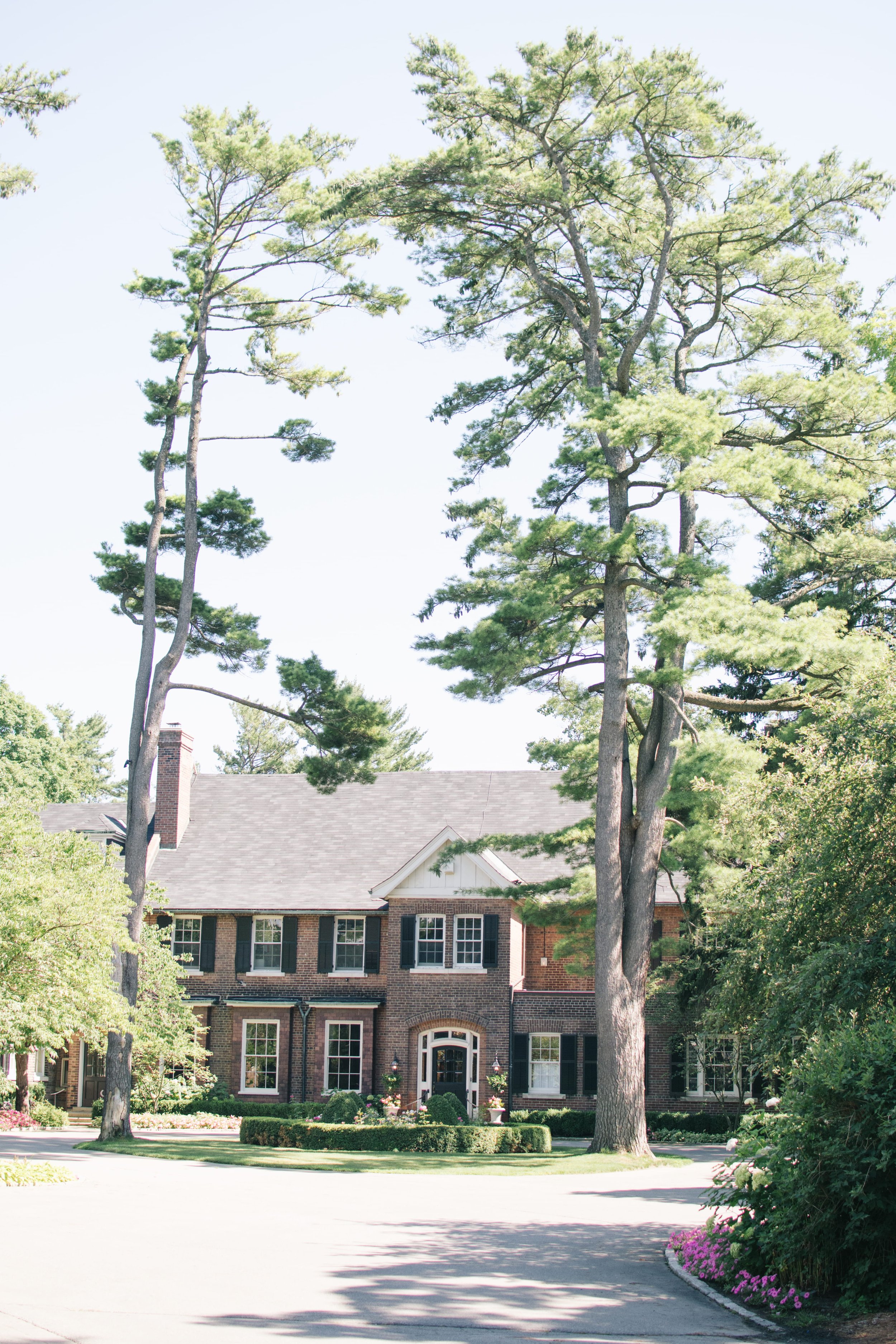 Exterior view of the Toronto Golf Club wedding venue, featuring the classic brick architecture and lush greenery, captured by Toronto wedding photographers.