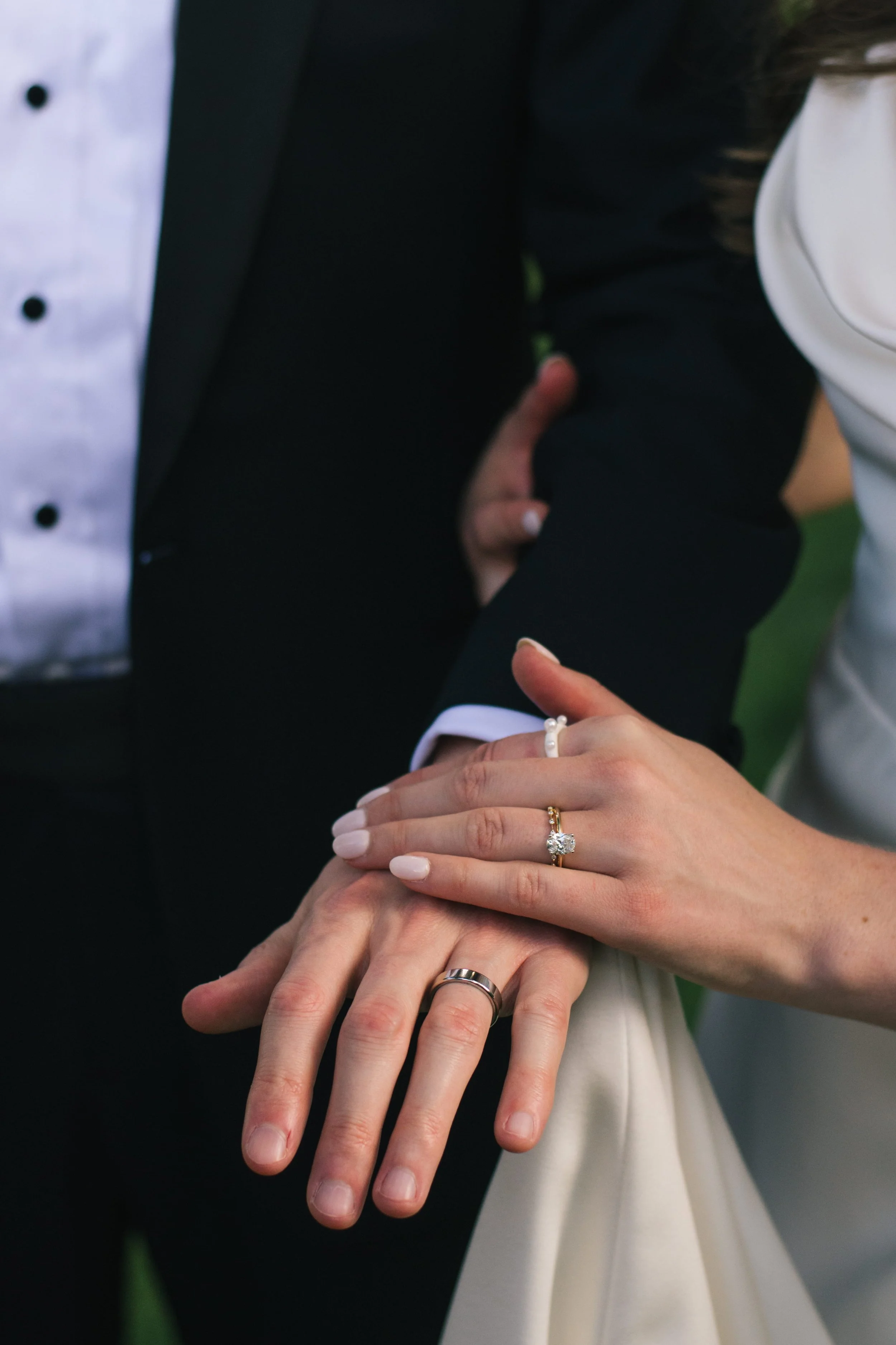 Close-up of bride and groom’s hands showing wedding and engagement rings during their wedding day