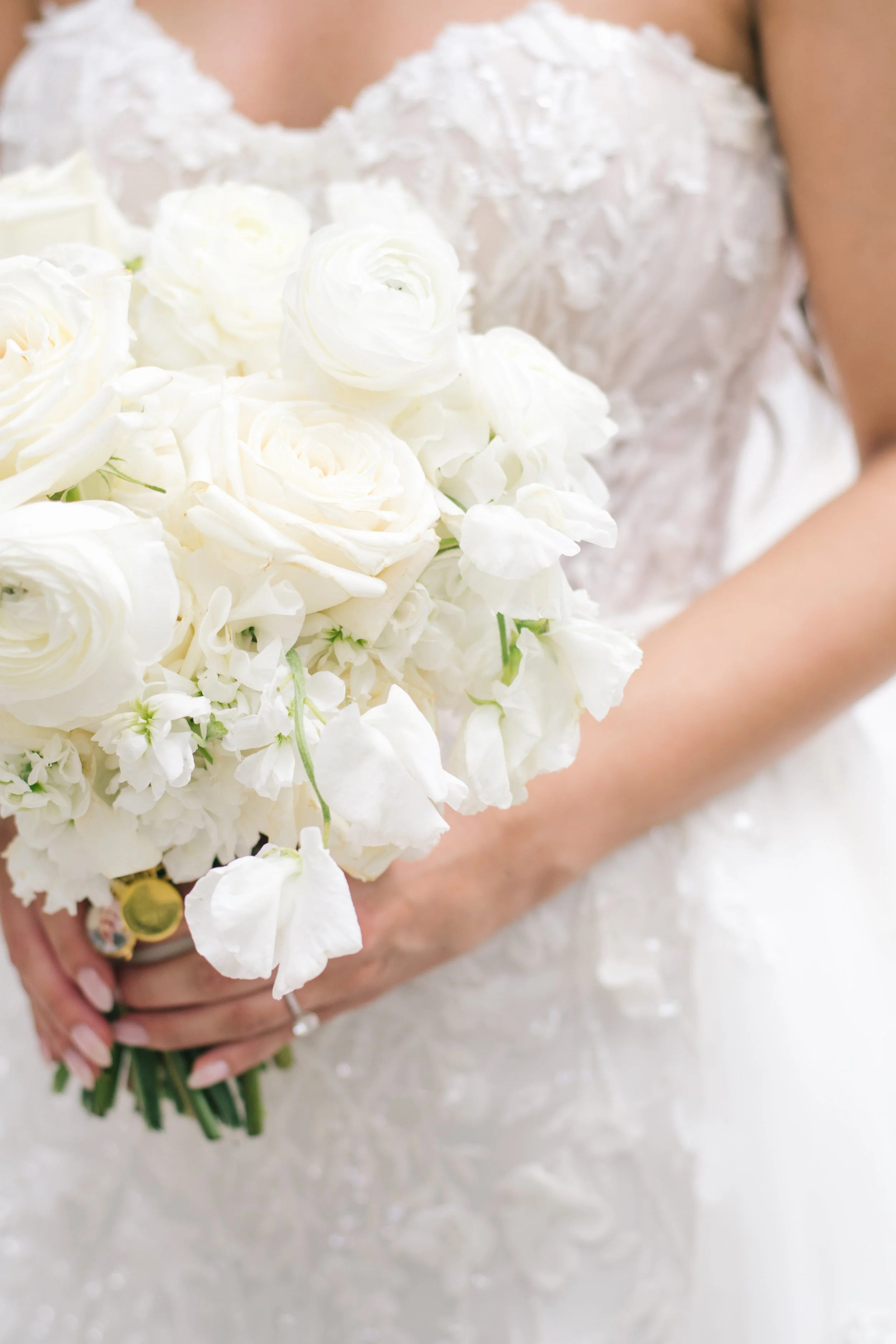 Close-up of a bride holding a white wedding bouquet with roses and soft florals