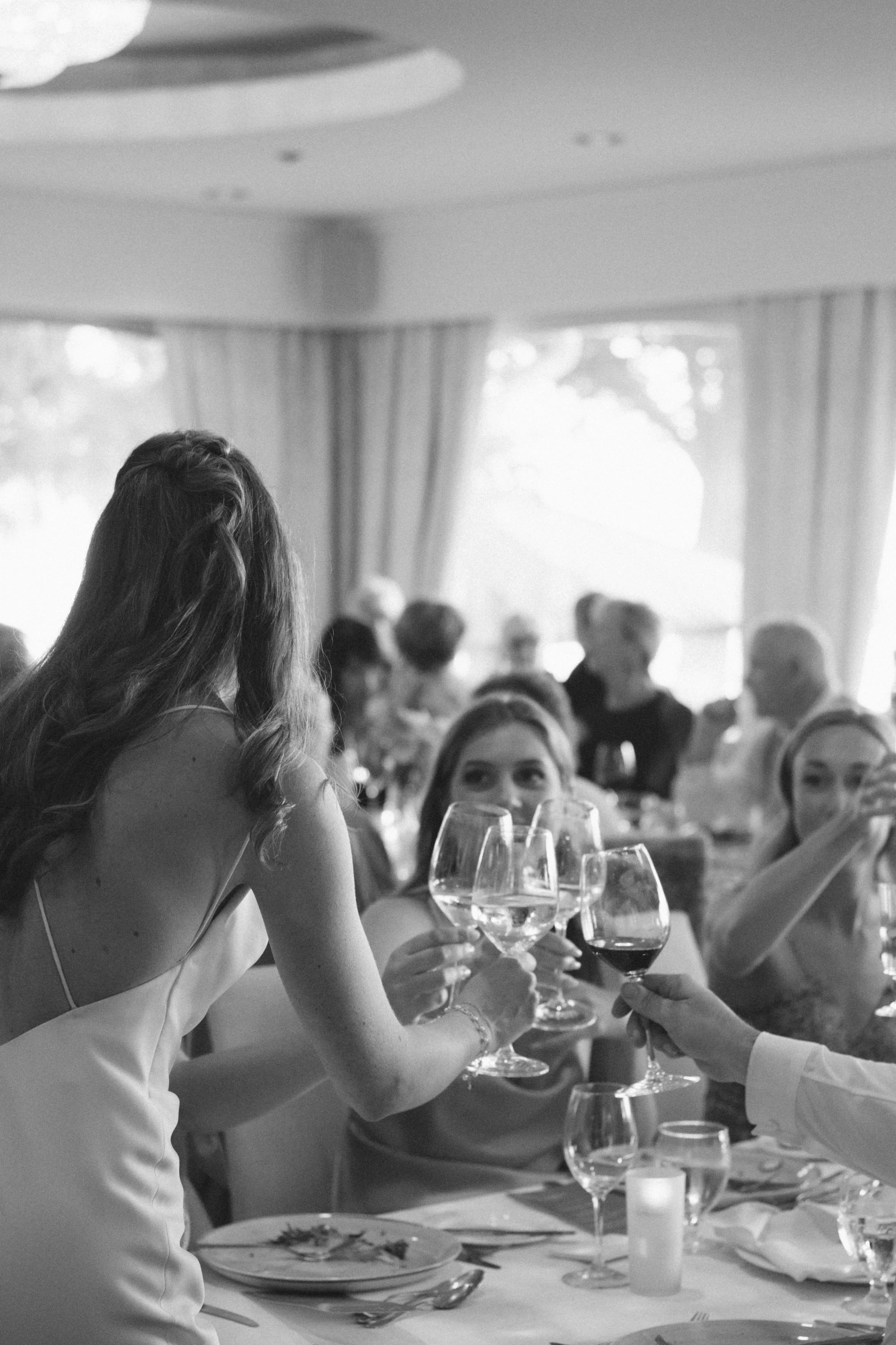 Bride clinking wine glasses with guests during a sophisticated wedding reception