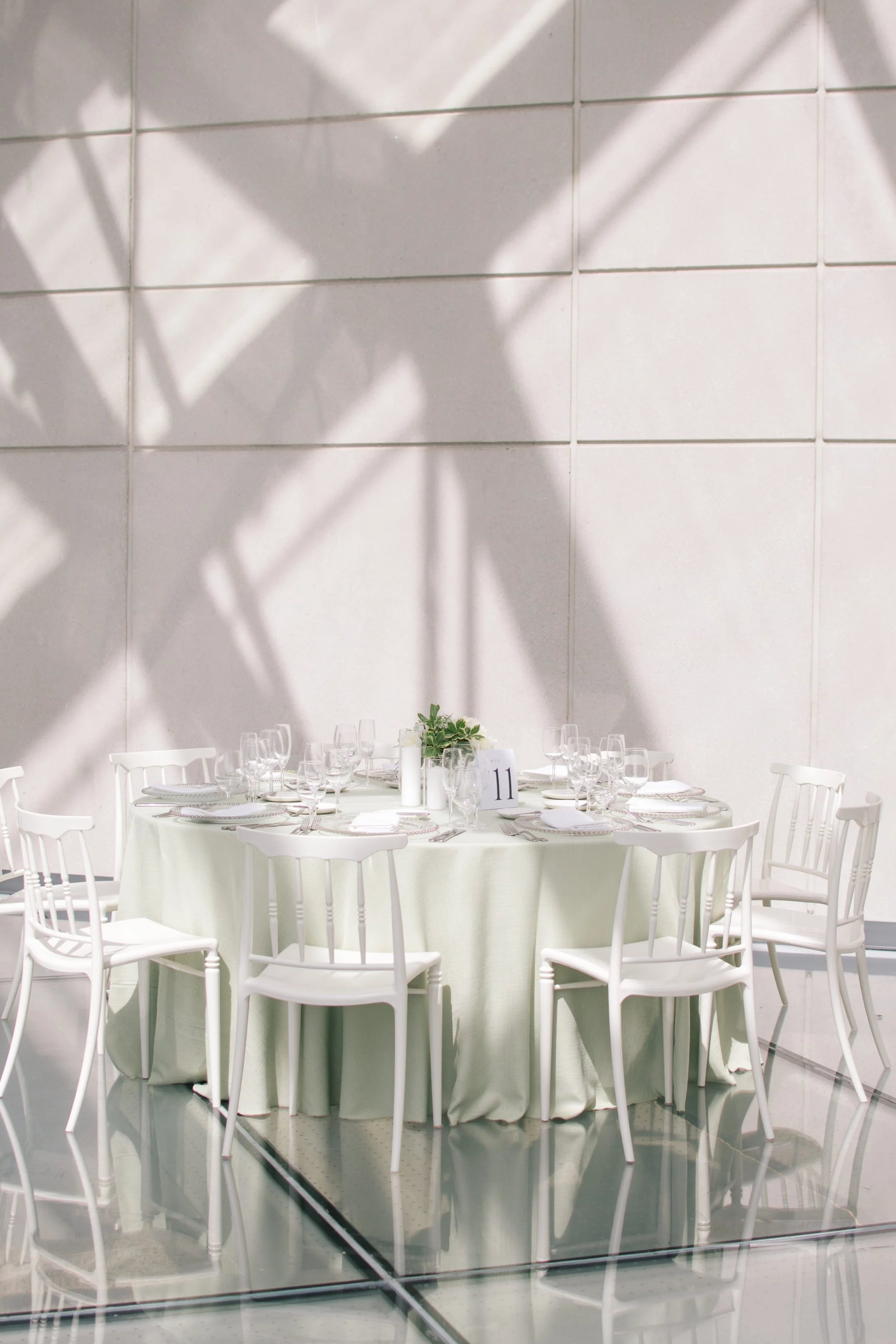 Modern wedding reception table styled with white chairs and soft natural light
