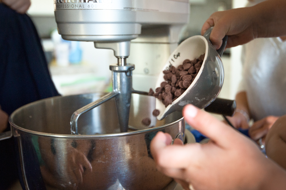 hands adding chocolate chips to mixer bowl