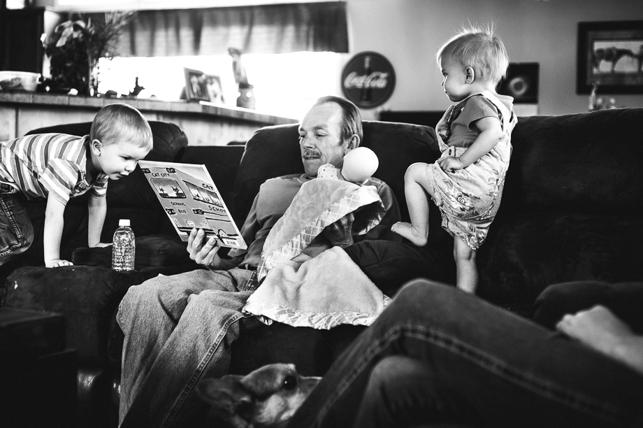 grandpa reading and holing doll while grandkids walk