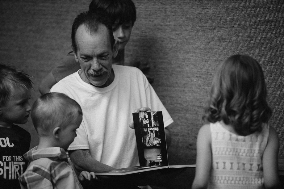 grandpa looking at photo album with grandkids