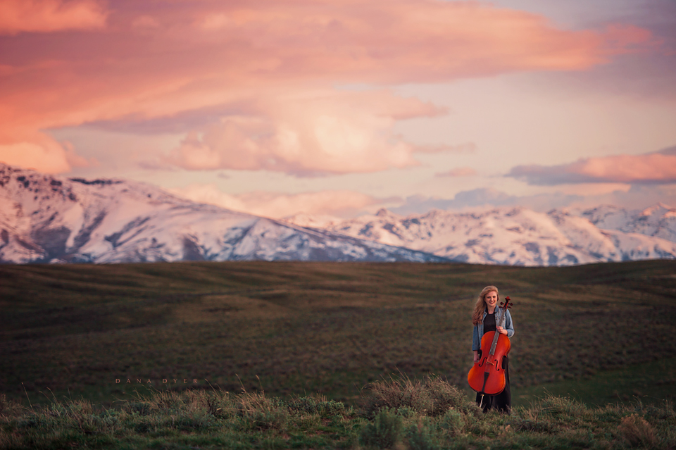 girl at sunset with cello and mountain range