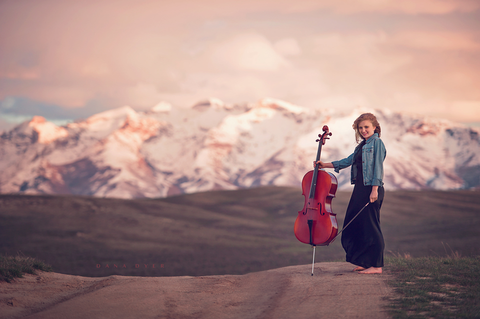 Girl with cello in front of mountain
