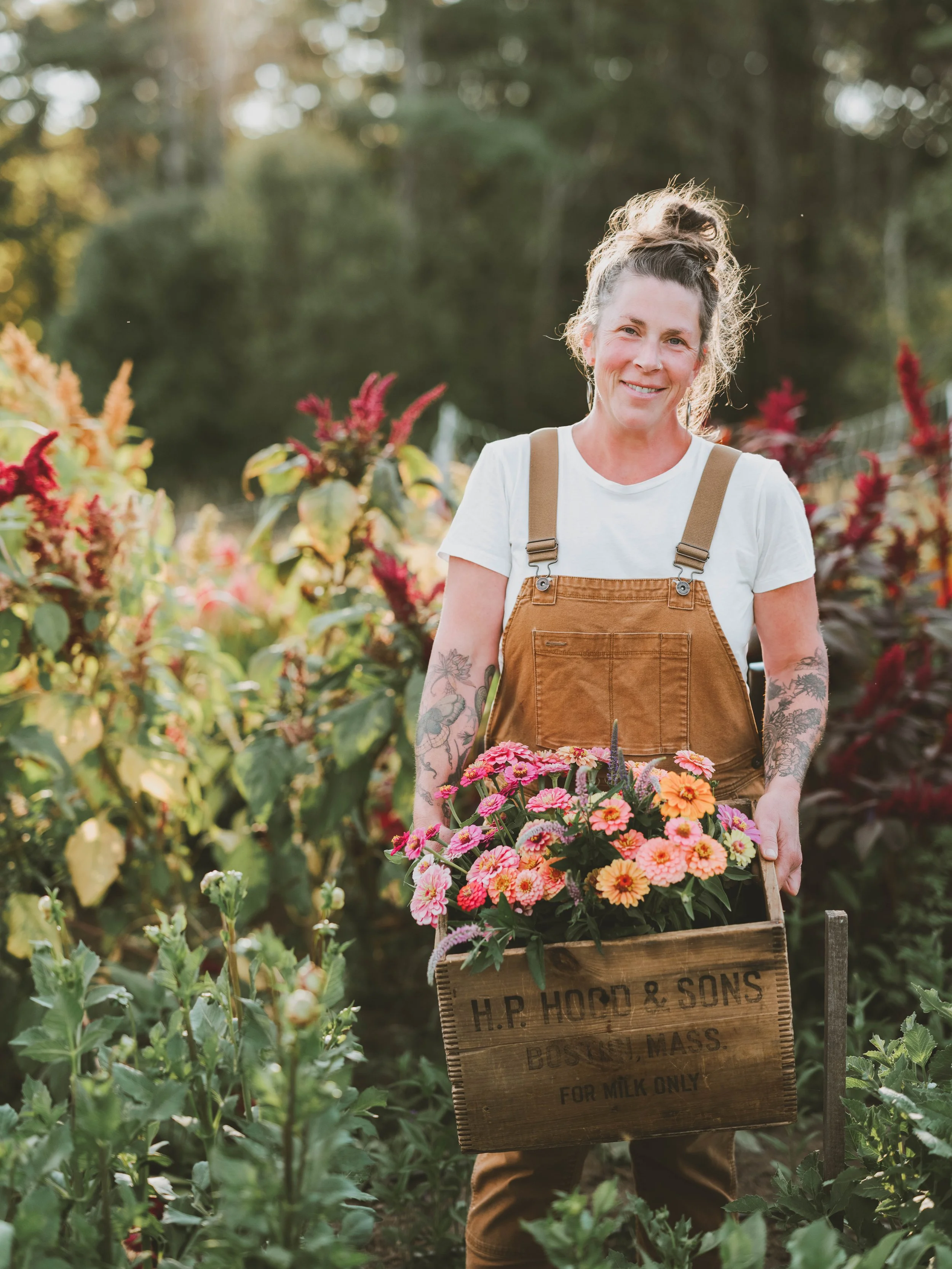 A female flower farmer smiling and holding cut flowers in her garden