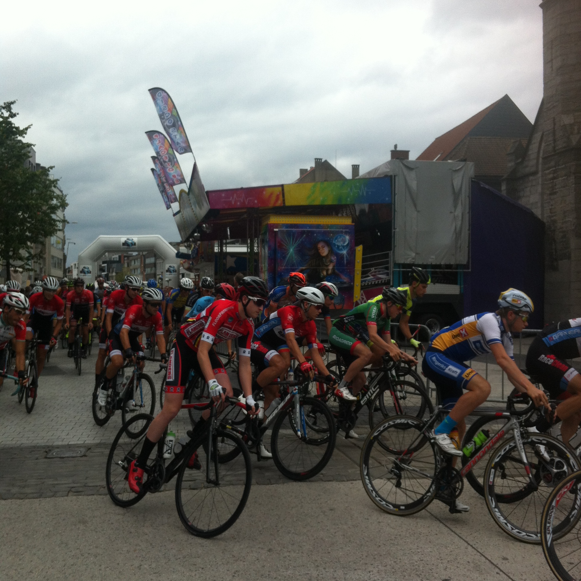 Conor (in red) at the Deinze start, passing the main kermis entertainment tent (beside the Church !)