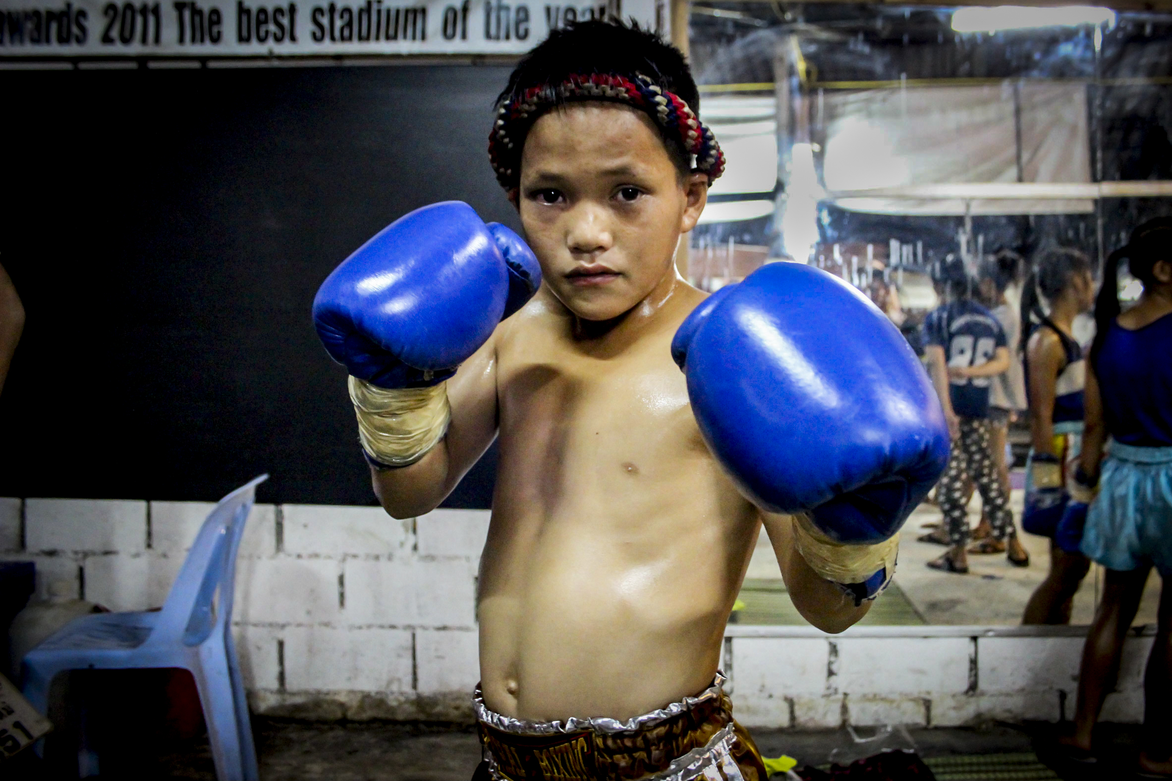 A young boy before his fight. In Thailand, many children are recruited to start practicing Muay Thai from as early as seven years old. For children and their families, Muay Thai is often seen as a way out of poverty. 