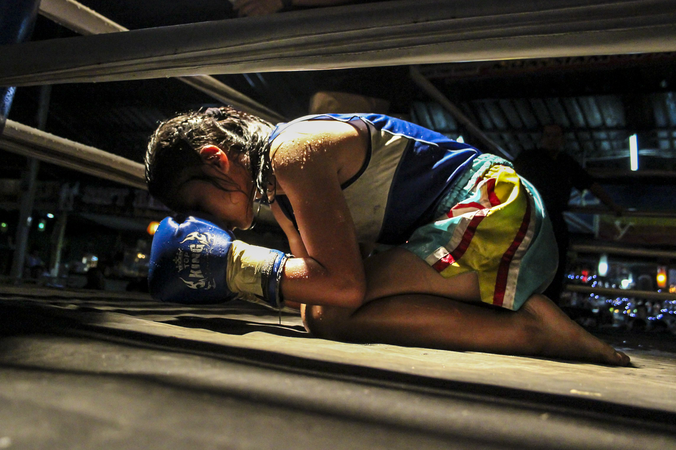 Muay Thai is more than just boxing in Thailand, it is a sport laden with sacred rituals and traditions. Before her fight, the teenage girl bows to the corner of each ring as part of 'wai kru ram muay'. 