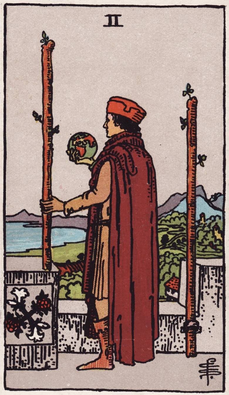 The Two of Wands from the Rider-Waite Colman Smith tarot deck shows a figure dressed in red with a globe in one hand and a wand in the other surveying his domain and planning a conquest.