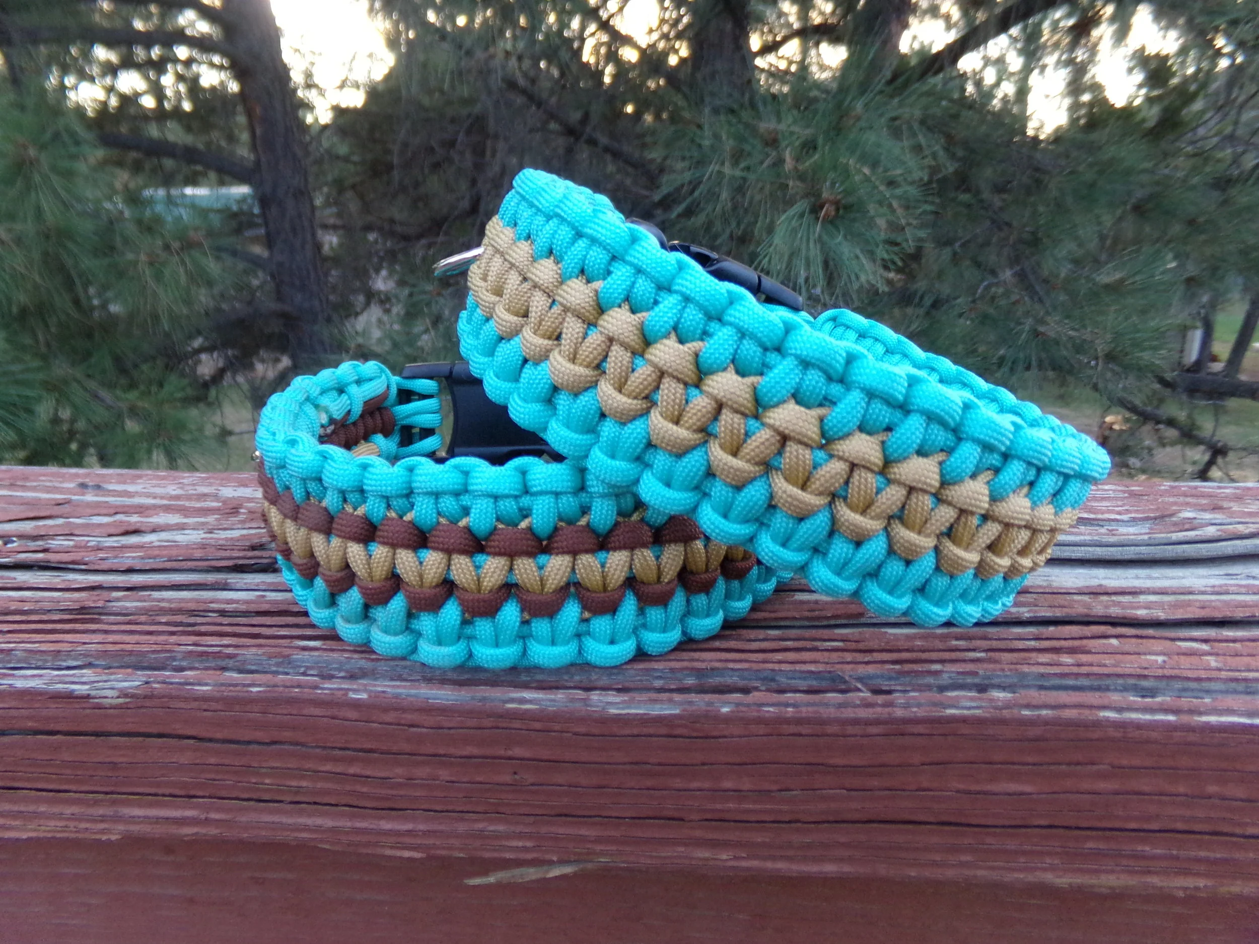 Turquoise and tan wide paracord dog collar pictured on a rustic deck railing