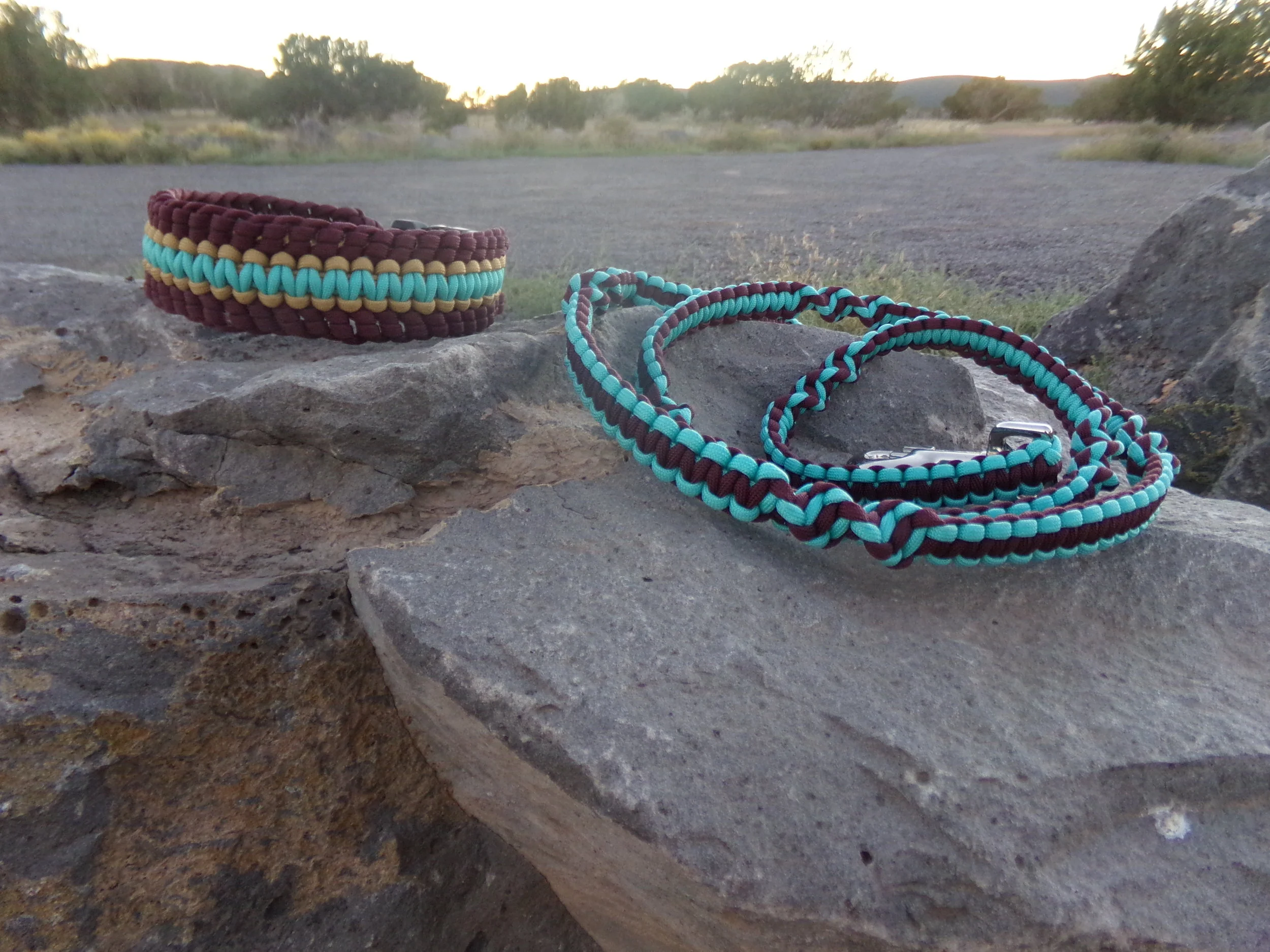 burgundy, turquoise, and gold paracord dog collar, Big Tesuque collection, pictured on a large rock with a matching burgundy and turquoise paracord leash, San Lorenzo collection