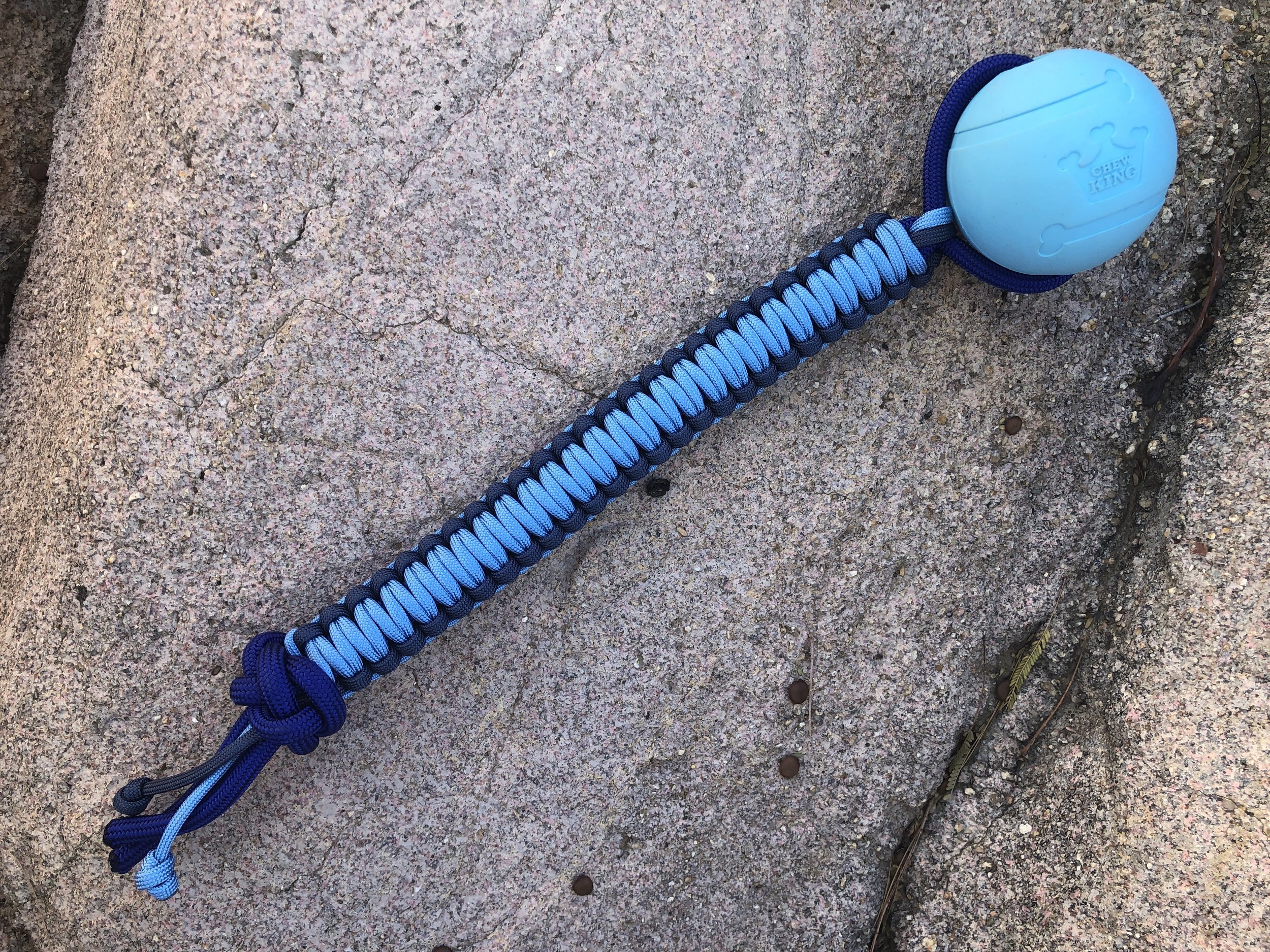 This is a 2.5" durable Chew King ball with a light blue and navy 550 paracord handle.
