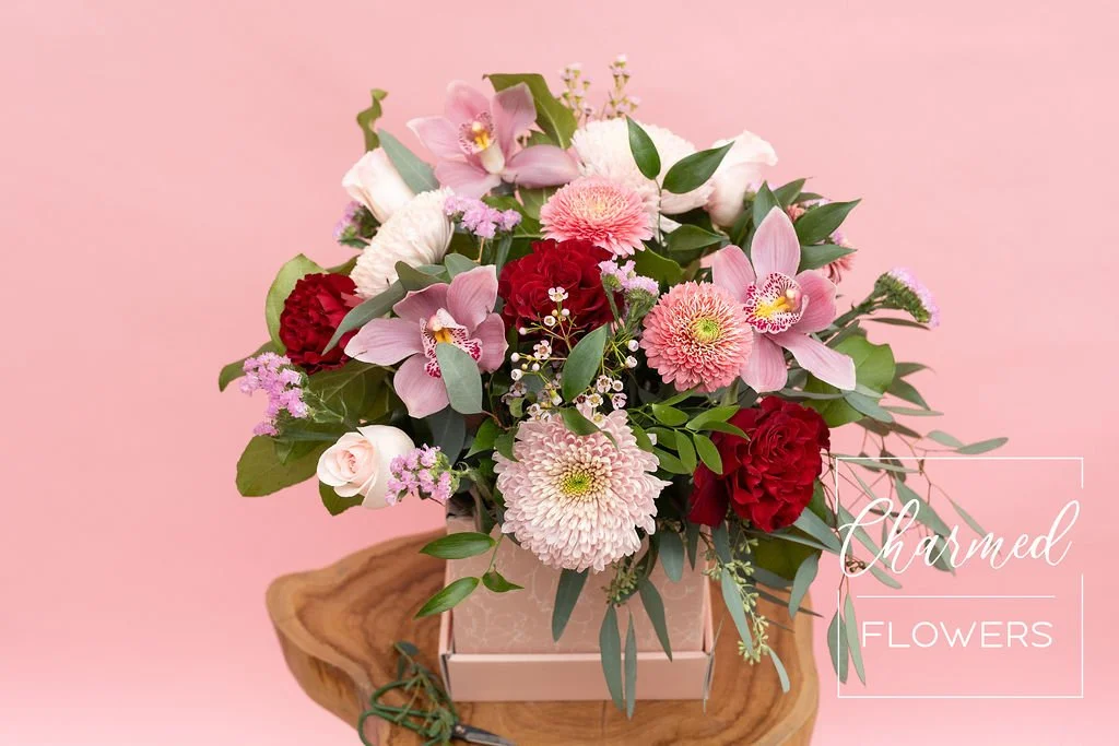 The Valentine's Charmed Box is a large arrangment featuring pink and red flowers in a pink box