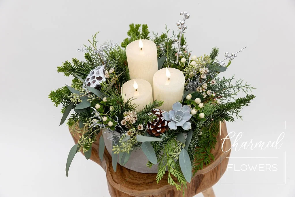 Evergreens styled in a cement bowl with 3 LED candles in the centre