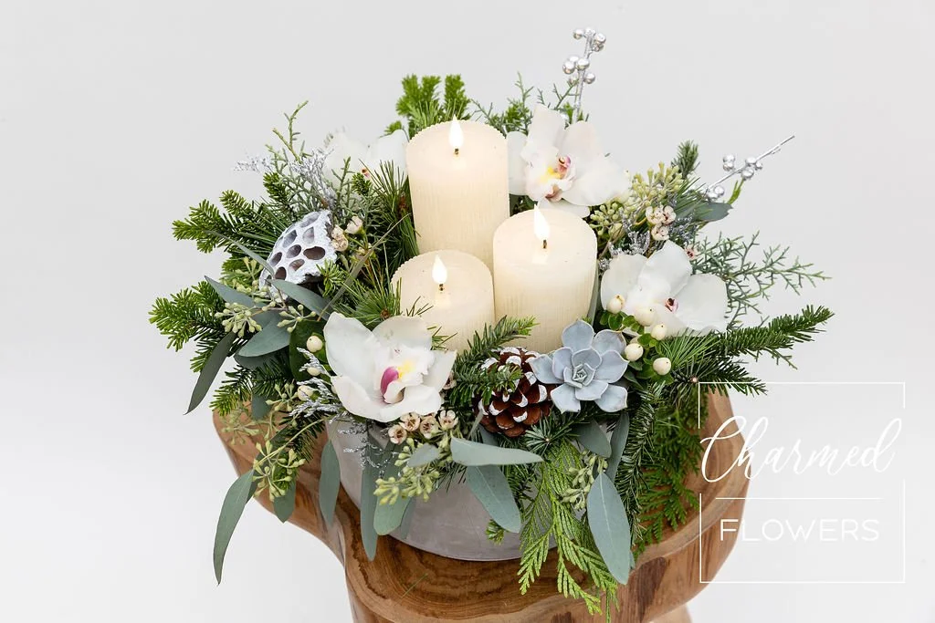 Evergreens styled in a cement bowl with 3 LED candles in the centre
