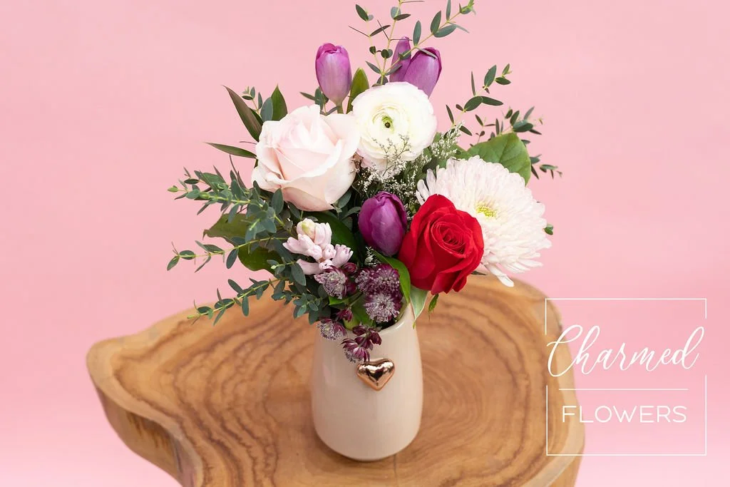 The Heart of Rose Gold Arrangment in a pink vase which features a dainty rose gold heart on the front of the vase