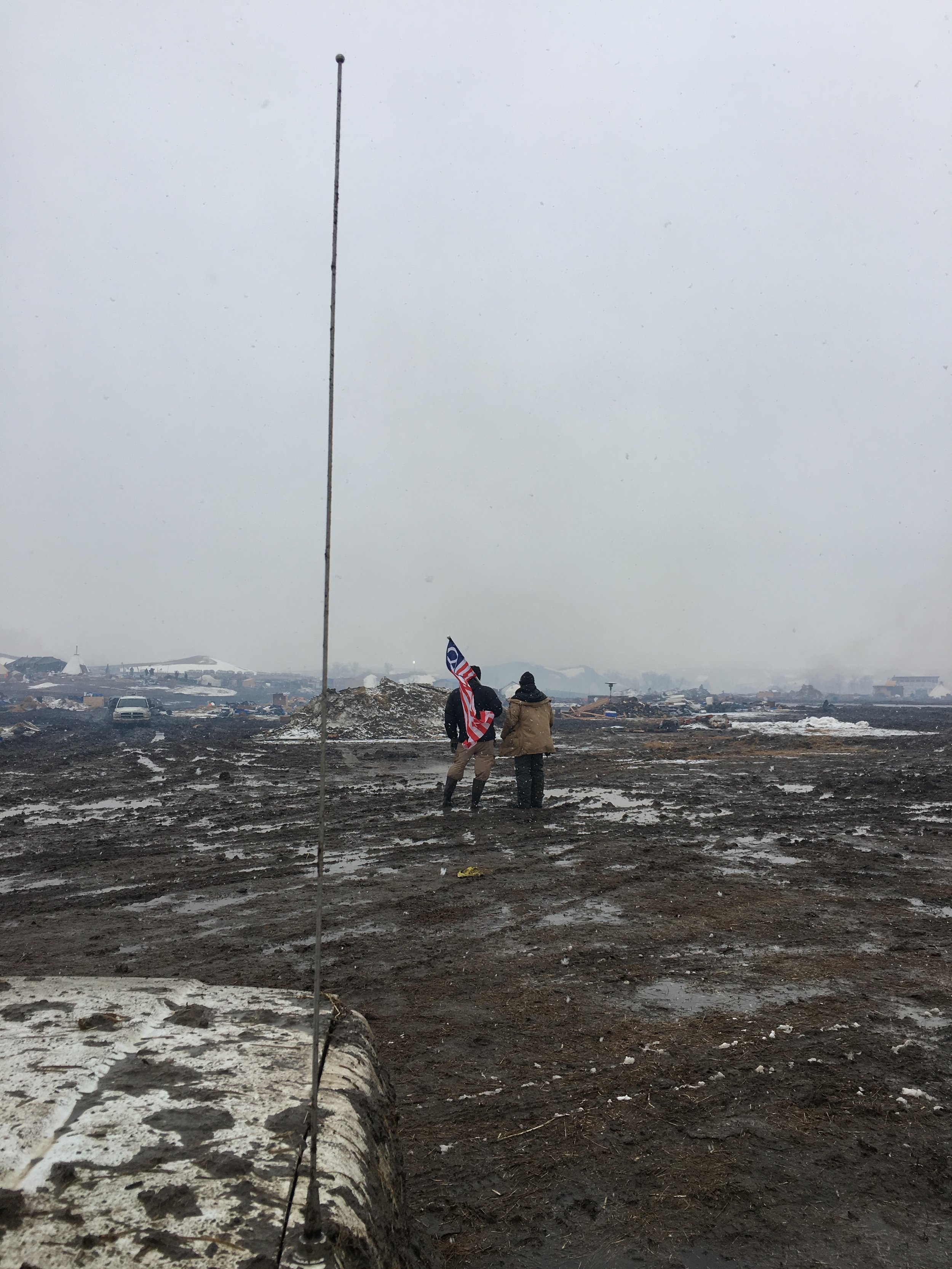Two water protectors look out over the evacuated Oceti Oyate camp (formerly Oceti Sakowin) as the 2 p.m. eviction deadline ticks past on Feb. 22, 2016. Photo by  Matt Halvorson .