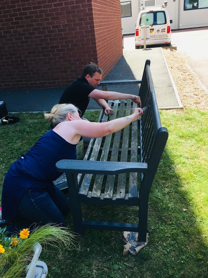 man and woman painting a memorial bench.JPG