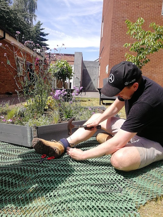 man nailing down grass reinforcement mesh pathway.jpg