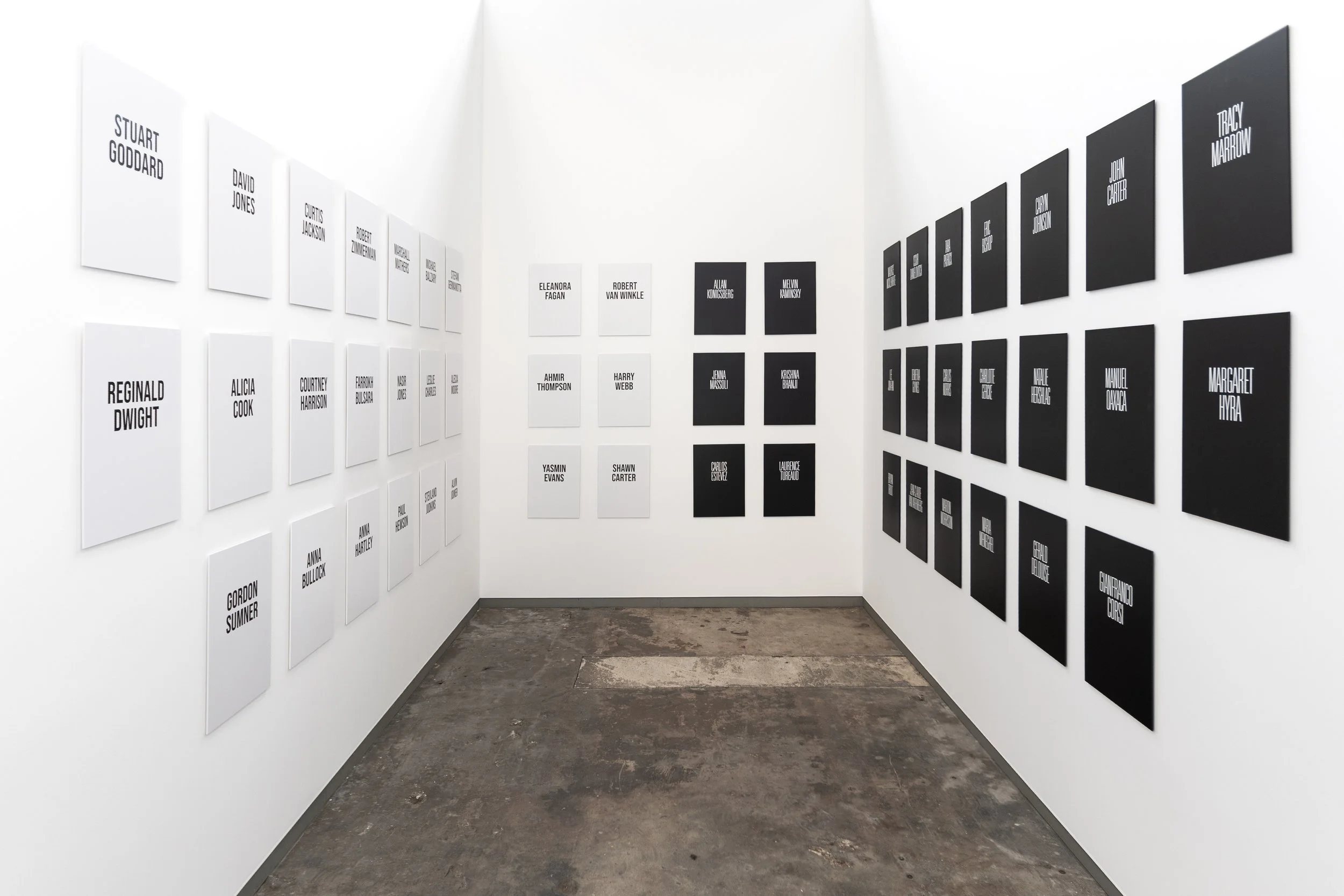 Text-based art installation of the Legends series at NordArt, featuring large-scale black-and-white title cards of iconic musicians and actors hung in linear order within the historic industrial architecture of the Carlshütte exhibition hall.